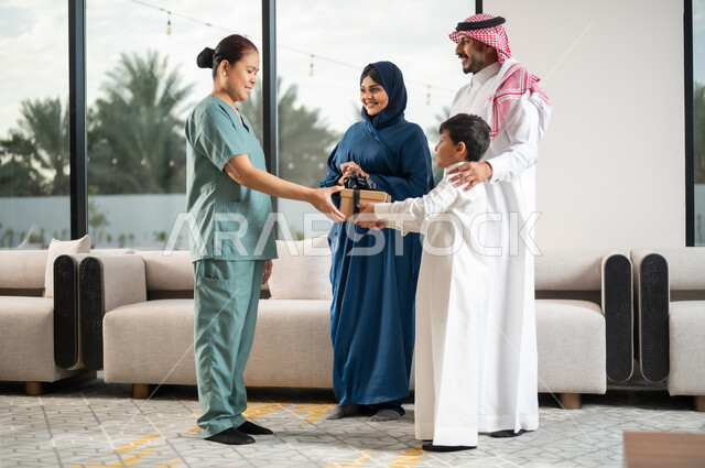Recruiting licensed and qualified foreign workers, a happy family atmosphere full of appreciation and respect, kindness in dealing with domestic maids in Saudi Arabia, women’s professions and jobs, a Saudi Gulf Arab child presenting a gift box to a Filipina maid for the quality of her service and performance.
