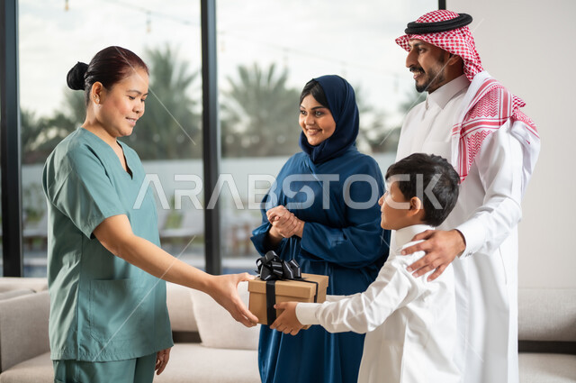الإحسان في التعامل مع الخادمات في البيوت في السعودية، استقدام العمالة الخارجية المرخصة والمؤهلة، أجواء عائلية سعيدة مليئة بالتقدير والاحترام، طفل عربي سعودي خليجي يقوم بتقديم علبة هدية لخادمة فلبينية لجودة خدمتها وأدائها، مهن ووظائف نسائية
