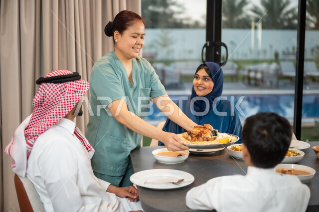 سفرة مليئة بالمأكولات العربية الشرقية, وجبات وأطباق وأصناف متنوعة شهية, عاملة أجنبية تقوم بتحضير المائدة, استقطاب العاملات الأجنبيات من الخارج، قضاء أوقات عائلية في إحدى الشاليهات الراقية، جلسات وأجواء سعيدة, عائلة عربية خليجية سعودية تستمتع بتناول الطعام