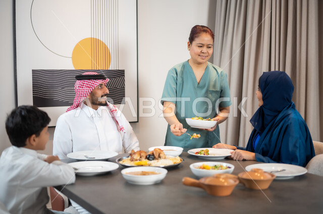استقطاب العاملات الأجنبيات من الخارج, قضاء أوقات عائلية في إحدى الشاليهات الراقية, جلسات وأجواء سعيدة, عائلة عربية خليجية سعودية تستمتع بتناول الطعام, سفرة مليئة بالمأكولات العربية الشرقية, وجبات وأطباق وأصناف متنوعة شهية, عاملة أجنبية تقوم بتحضير المائدة