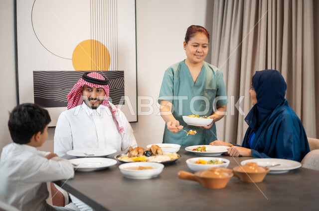 قضاء أوقات عائلية في إحدى الشاليهات الراقية, جلسات وأجواء سعيدة, عائلة عربية خليجية سعودية تستمتع بتناول الطعام, سفرة مليئة بالمأكولات العربية الشرقية, وجبات وأطباق وأصناف متنوعة شهية, عاملة أجنبية تقوم بتحضير المائدة, استقطاب العاملات الأجنبيات من الخارج