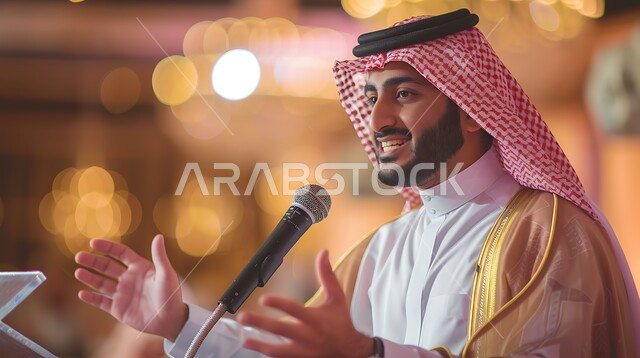 التفاعل مع الجمهور على خشبة المسرح، إلقاء خطاب وندوة ثقافية، المسرحيات الممتعة والندوات التثقيفية، الأنشطة الترفيهية والعروض المسرحية، المناسبات والأعياد السعيدة في السعودية، رجل عربي خليجي سعودي يرتدي الزي التقليدي يحمل بيده مايكروفون