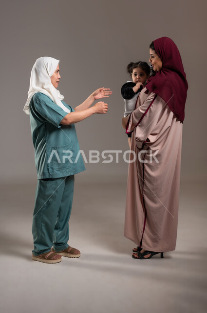 The modesty of women in dealing with maids in Saudi homes, a portrait of a Filipina nanny trying to carry the child, the tenderness of mothers and taking care of children, an Arab Gulf girl who refuses to leave her mother’s embrace, full length of the body, gray background