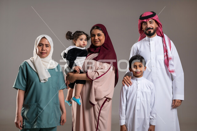 قضاء أوقات ممتعة، توثيق اللحظات بصورة عائلية جماعية، بورتريه لعائلة عربية خليجية سعودية وعاملة فلبينية يقومون بالتقاط الصور  , أجواء مليئة بالحب، الاهتمام بمشاعر الغير، خلفية رمادية