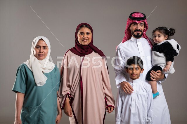 قضاء أوقات ممتعة، توثيق اللحظات بصورة عائلية جماعية، بورتريه لعائلة عربية خليجية سعودية وعاملة فلبينية يقومون بالتقاط الصور  , أجواء مليئة بالحب، الاهتمام بمشاعر الغير، خلفية رمادية