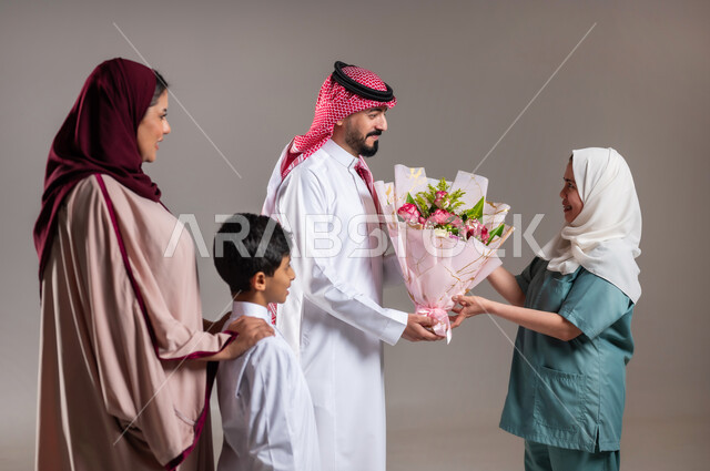 مشاركة وتقديم الهدايا بالمناسبات وأعياد الميلاد, بورتريه لعائلة عربية سعودية خليجية تقوم بتقديم باقة من الزهور لعاملة فلبينية بايماءات السعادة و السرور, أجواء مليئة بالتقدير والاحترام، الاهتمام بمشاعر الغير، خلفية رمادية