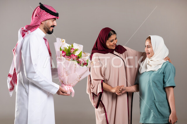 القيام بالمهام والأعمال المنزلية الروتينية، الإحسان في التعامل مع الخادمات في البيوت السعودية، بورتريه لرجل وامرأة عربيان سعوديان خليجيان يقومان بتقديم باقة زهور للعاملة الفلبينية لجودة خدمتها وادائها، مهن ووظائف نسائية، خلفية رمادية