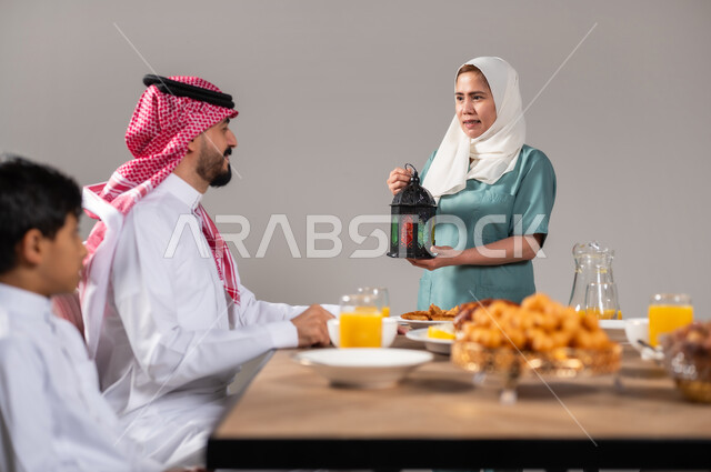ضيافة رمضانية لذيذة، طبق اللقيمات ذهبية اللون، حلا الزلابيات الشرقي، كرات العجين المقلية الصغيرة، المناسبات والأعياد في المملكة العربية السعودية، تعظيم و تقدير الشهر الفضيل، عاملة منزلية فلبينية تحمل فانوس ملون، خلفية رمادية