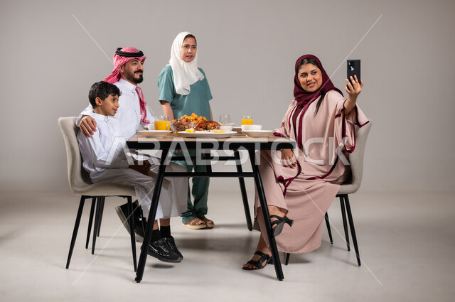 التقاط صورة سيلفي تذكارية، بورتريه لعاملة فلبينية تقوم بتحضير سفرة رمضان و وضع الطبق الرئيسي عليها, المقبلات و الاصناف العربية الشرقية, ايماءات السعادة بمناسبة قدوم الشهر الفضيل, الاحتفال بالاعياد و المناسبات الاسلامية, لمة الاهل على طاولة الطعام، خلفية رمادية