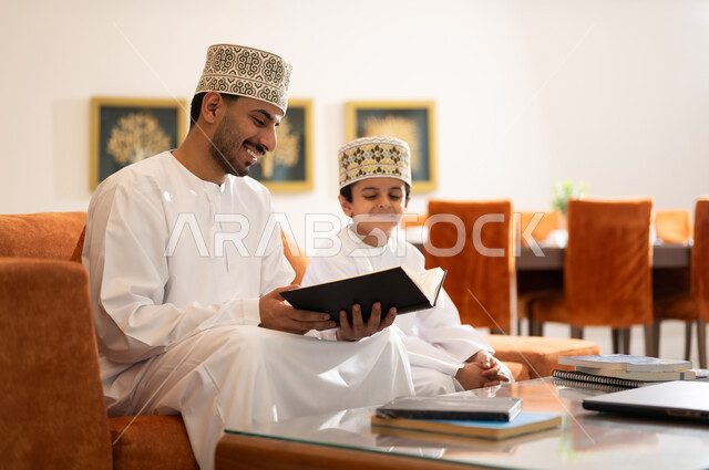 تنميه قدرات الاطفال بالتعلم، تشجيع وتطوير الاطفال بحل الواجبات المدرسيه المنزليه، بورتريه لأب عربي خليجي عماني يرتدي الدشداشه والكمه يقوم بمساعده ابنه في التعليم والقراءه، الانشطة التعليمية الالكترونيه  وانجاز الدروس والواجبات عن بعد باستخدام جهاز الايباد المحمول