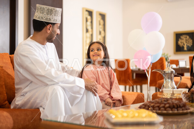 الزيارات العائلية وتبادل التهنئات والمعايدات بين أفراد الأسرة بإيماءات الفرح والسعادة, أجواء العيد بين الأهل, بورتريه لعائلة عربية خليجية عمانية تحتفل بالعيد السعيد, تقديم الحلويات والضيافة الشعبية, طقوس الأعياد والمناسبات الاسلامية في سلطنة عمان