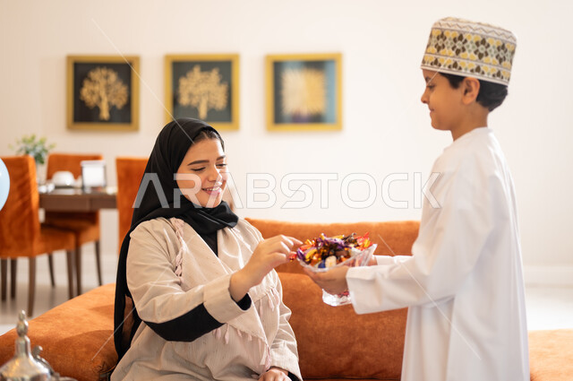 الزيارات العائلية وتبادل التهنئات والمعايدات بين أفراد الأسرة بإيماءات الفرح والسعادة, أجواء العيد بين الأهل, بورتريه لعائلة عربية خليجية عمانية تحتفل بالعيد السعيد, تقديم الحلويات والضيافة الشعبية, طقوس الأعياد والمناسبات الاسلامية في سلطنة عمان