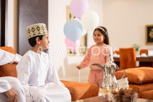 Family visits and the exchange of congratulations and greetings between family members with gestures of joy and happiness, the Eid atmosphere among the family, a portrait of an Arab Gulf-Omani family celebrating the Happy Eid, the provision of sweets and popular hospitality, holiday rituals and Islamic occasions in the Sultanate of Oman