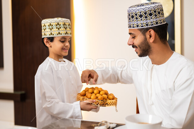 تجهيز وتحضير سفرة الإفطار، اجتماع الأسرة حول طاولة الطعام المليئه بأصناف المأكولات و المقبلات الشهية، ديكورات وأجواء رمضانية، بورتريه لعائله عربيه خليجيه عمانيه ترتدي الزي العماني التقليدي مجتمعين حول مائده الطعام يشاركون بعضهم طعام الافطار