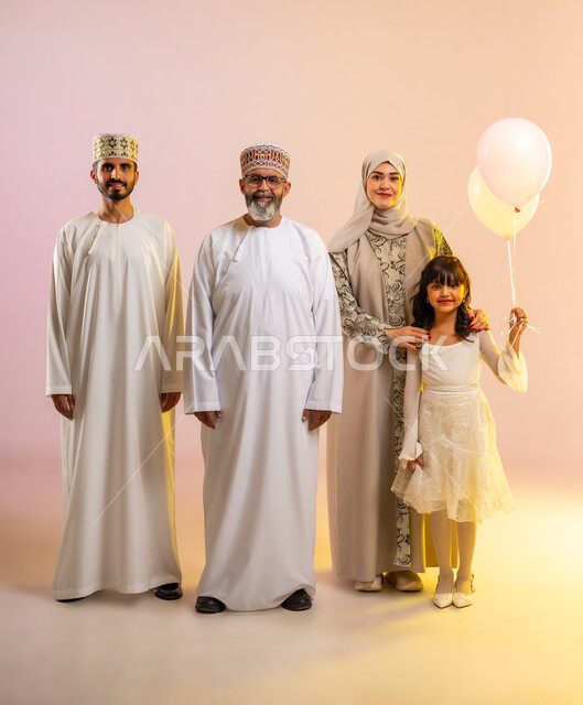 الاحتفال بالأعياد الإسلامية في سلطنة عمان، أجواء العيد برفقة الأسرة, تقوية الروابط العائلية ومشاعر الحبة والمودة، بورتريه لعائلة عربية خليجية عمانية تحتفل بالمناسبات المبهجة برفقة بعضها البعض بإيماءات السعادة، تبادل الهدايا والمعايدات بين الأهل، خلفية ملونة