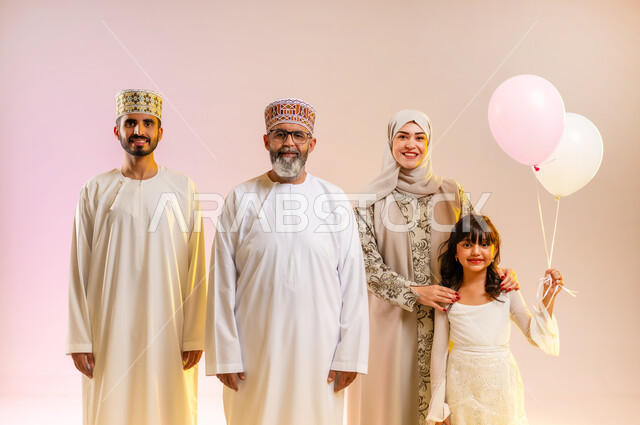 طقوس عطلة الأعياد في سلطنة عمان، أجواء العيد برفقة الأسرة, تقوية الروابط العائلية ومشاعر المحبة والمودة، بورتريه لعائلة عربية خليجية عمانية تحتفل بالمناسبات برفقة بعضها البعض بإيماءات السعادة، تبادل الهدايا والمعايدات بين الأهل، خلفية ملونة