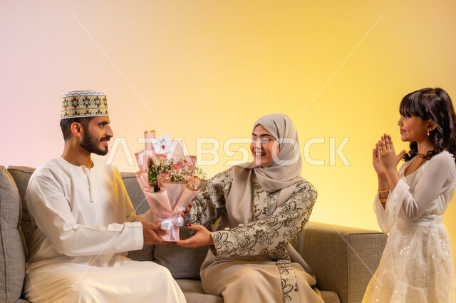 إهداء الورود والقيام بالمفاجآت، طقوس العيد في سلطنة عمان, تقوية الروابط العائلية، بورتريه لعائلة عمانية تحتفل بالأعياد والمناسبات برفقة بعضها البعض بإيماءات السعادة، قضاء الأوقات الممتعة برفقة الأهل، تبادل الهدايا والمعايدات بين أفراد الأسرة، خلفية ملونة