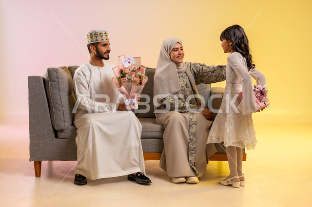 البر بالوالدين و تقديرهم، استقبال العيد بالهدايا والأزهار،  المودة والمحبة بين أفراد الأسرة، تقوية الروابط العائلية، بورتريه لفتاة عربية خليجية عمانية تحمل بيدها علبة هدية مغلفة، عائلة عمانية تحتفل بالأعياد والمناسبات بسعادة، خلفية ملونة