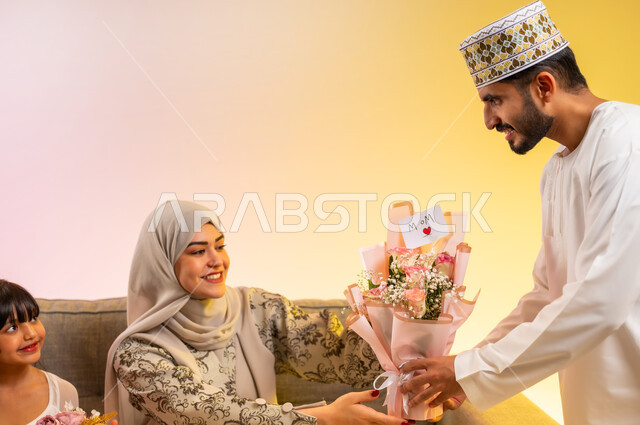 Love and compassion between spouses, strengthening marital ties, surprises and presenting Eid gifts to the mother, a close-up portrait of an Omani Gulf Arab man wearing a dishdasha and a cuff, presenting roses to his wife, an Omani family celebrating the coming of Eid with gestures of happiness, a colorful background.