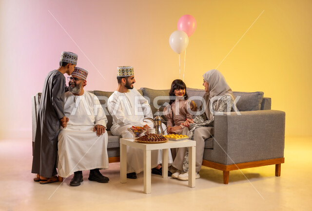 مفهوم البر والرضا بتقبيل رأس الجد ومعايدته في صباح العيد، تجمع العائلة والجلوس برفقة بعضها البعض بسعادة, ارتداء الثياب العمانية التقليدية لاستقبال العيد المبارك, بورتريه لعائلة عربية خليجية عمانية تحتفل بالمناسبات الاسلامية , خلفية ملونة