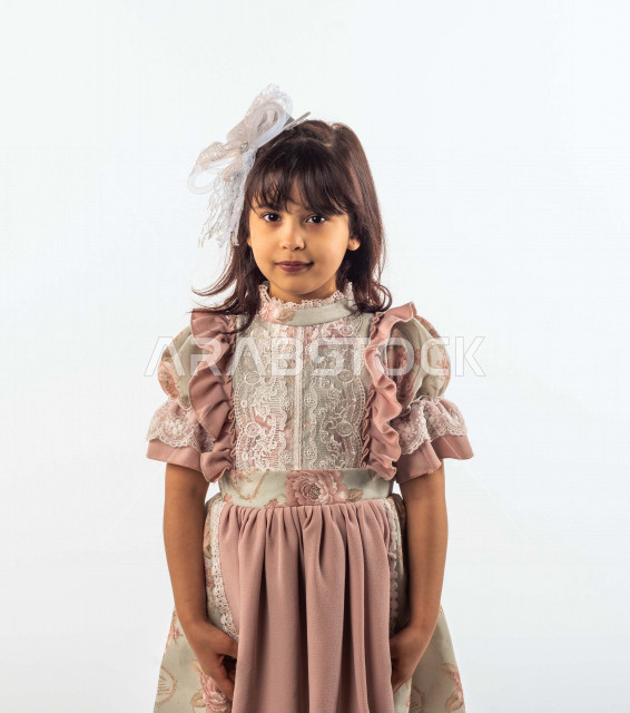 خلفية بيضاء لفتاه صغيرة سعودية خليجية مبتسمة وجميلة ، تنظر الى الكاميرا بإيماءات وجه ويدين مختلفة , بورتريه لطفلة سعودية خليجية سعيدة ترتدي لباس العيد الانيق , الاحتفال بعيد الفطر السعيد ، عيد الفطر المبارك