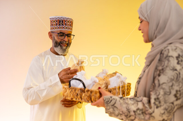 Wearing traditional Omani costumes, offering popular sweets on holidays, rituals of celebrations and happy occasions in the Sultanate of Oman, close-up portrait of a veiled woman distributing hospitality, an Omani Gulf Arab family celebrating the blessed Eid, showing feelings of joy and happiness, colorful background