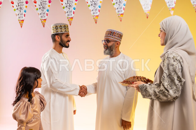 التهنئة والمصافحة بين أفراد الأسرة, أجواء البهجة والفرح في العيد, بورتريه لعائلة عربية خليجية عمانية تحتفل بالأعياد الاسلامية, طقوس الاحتفالات والمناسبات السعيدة، تقديم الحلويات التقليدية والمأكولات الشهية, إظهار مشاعر المودة والمحبة العائلية, خلفية ملونة