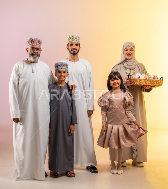 Eid celebration rituals and wearing new clothes, a portrait of an Arab Gulf Omani family celebrating Islamic holidays, standing and looking at the camera with gestures of happiness and joy, offering traditional sweets and delicious food, showing feelings of family affection and love, colorful background