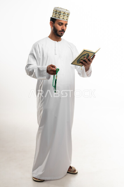 تدبر آيات القران الكريم، الشعور بالخشوع والطمأنينة، بورتريه لشاب عربي خليجي عماني يرتدي الدشداشة والكمه يحمل بيده المصحف الشريف والسبحة، الإكثار من ذكر الله تعالى من خلال الاستغفار والدعاء، الاجتهاد في العبادة، التقرب الى الله في شهر رمضان، خلفية بيضاء