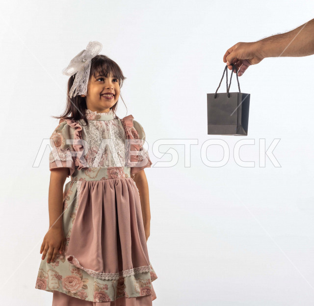 خلفية بيضاء لفتاه صغيرة سعودية خليجية مبتسمة وجميلة ، بإيماءات وجه ويدين مختلفة , طفلة سعودية خليجية سعيدة ترتدي لباس العيد الانيق , الاحتفال بعيد الفطر السعيد ، عيد الفطر المبارك , تقديم الهدايا في العيد