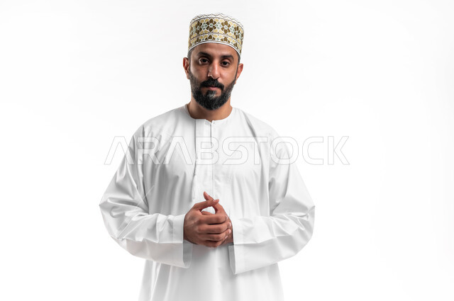 حل المشكلات واتخاذ القرارات، الشعور بالضيق والملل، التمعن والتركيز لإيجاد الحل لمشكلة ما, بورتريه مقرب لشاب عربي خليجي عماني يرتدي الدشداشة و الكمه ينظر الى الكاميرا بإيماءات الجدية والانزعاج، مفهوم التفكير والحيرة، خلفية بيضاء