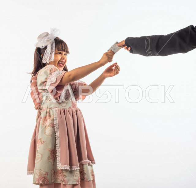 خلفية بيضاء لفتاه صغيرة سعودية خليجية مبتسمة وجميلة ، تأخذ العيدية بيدها بإيماءات وجه ويدين مختلفة , بورتريه لطفلة سعودية خليجية سعيدة ترتدي لباس العيد الانيق , الاحتفال بعيد الفطر السعيد ،عيد الفطر المبارك, تقديم العيدية للأطفال في عيد الفطر المبارك