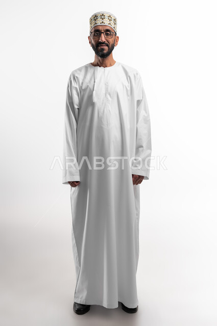 Attention to external appearance, the concept of elegance in wearing traditional clothes, a portrait of an elderly Omani Arab man wearing a dishdasha and a cuff, looking at the camera with a smiling expression, white background.