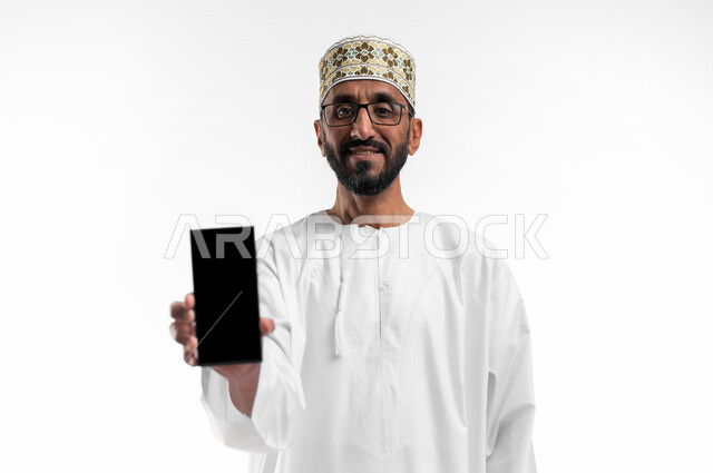 The concept of technical and technological developments, a portrait of an old Omani Arab man wearing a dishdasha and a cuff, displaying a blank black screen on a mobile phone, keeping pace with modern progress, a white background.