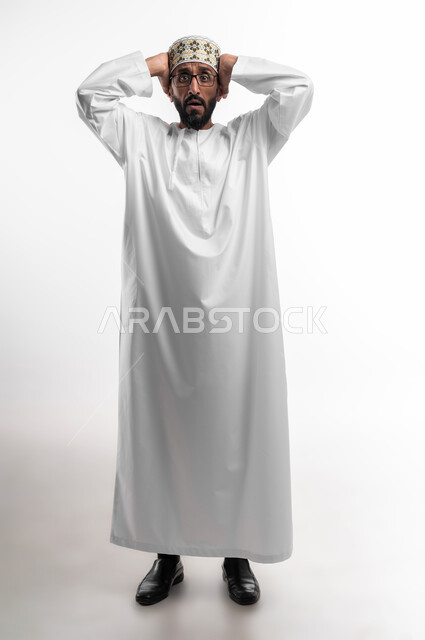 تعابير وجه تدل على حدوث مصيبة ما، بورتريه لرجل عربي عماني شايب يرتدي الدشداشة والكمه يضع يده على رأسه تظهر عليه علامات الحيرة والوقوع في مشكلة، عدم القدرة على مسك زمام الأمور وفقدان السيطرة، خلفية بيضاء