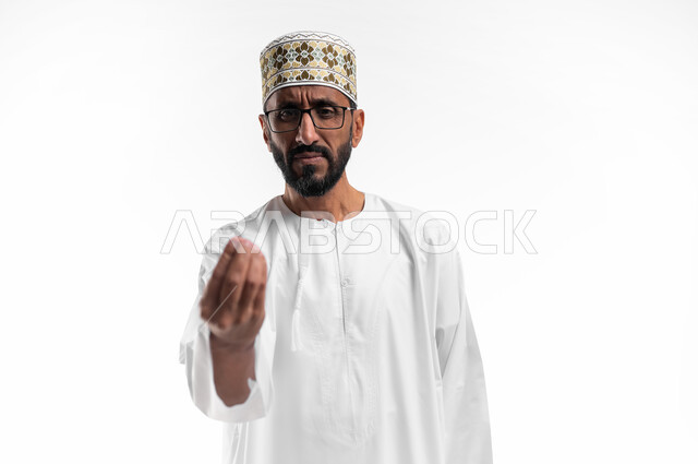 حركة يد تعني خفض الصوت والهدوء، ايماءات وجه ويدين تدل على محاولة تهدئة نقاش حاد، بورتريه لرجل عربي عماني شايب يرتدي الدشداشة والكمه تظهر عليه علامات الانزعاج وعدم الراحة، طريقة الطلب بأدب واحترام، خلفية بيضاء