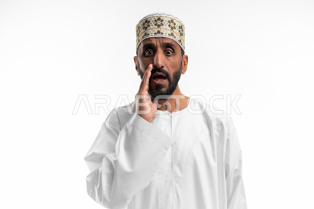 ايماءات خوف وتحذير، بورتريه لرجل عربي عماني شايب يرتدي الدشداشة والكمه يقوم بمناداة شخص ما بالخفية، تعابير وجه تدل على التنبيه من حدوث مصيبة ما، خلفية بيضاء