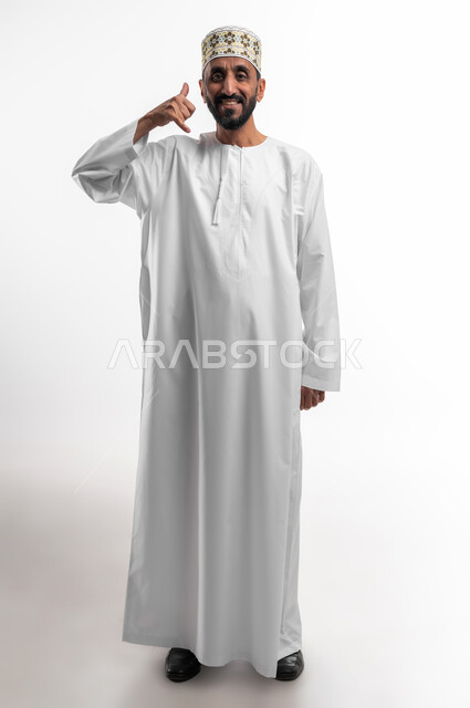حركة يد تدل على الاتصال بالاصدقاء والاقارب وتبادل المعلومات، طريقة الرد على المكالمات الهاتفية، بورتريه لرجل عماني شايب يرتدي الدشداشة والكمه تظهر عليه علامات الفرح والسرور، تلقي أخبار سارة عبر الجوال، خلفية بيضاء