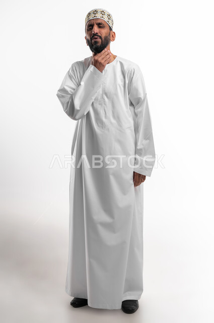 الشعور بألم في البلعوم, الحاجة إلى العلاج والدواء, مفهوم الاهتمام بالصحة, الاصابة بنزلة برد والتهاب الحلق, بورتريه لرجل كبير السن عربي خليجي عماني يرتدي الكمه والدشداشة ويضع يديه على حلقه ويشعر بالاختناق, خلفية  بيضاء