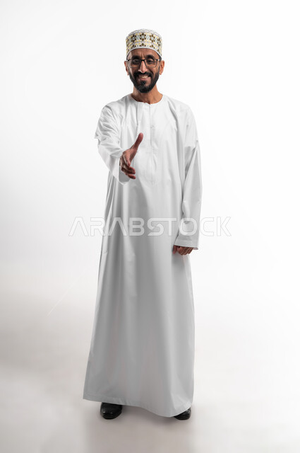مد اليد لرد السلام، المصافحة وإلقاء التحية، بورتريه لرجل عماني شايب يرتدي الزي التقليدي (الدشداشة البيضاء والكمه)، الجسم بالطول الكامل، تعابير فرح وسرور، النظر للكاميرا بإيماءات السعادة، خلفية بيضاء