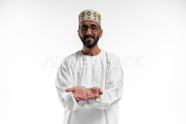 حركة يد تدل على طلب العون والمساعدة، مد الكفين للإمام اشارةً للحاجة، بورتريه لرجل عماني شايب يرتدي الدشداشة والكمه ونظارات طبية، الزي التقليدي للرجال في سلطنة عمان، ايماءات عجز وترجي، خلفية بيضاء