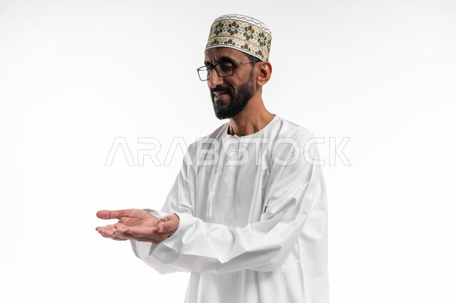 حركة يد تدل على طلب العون والمساعدة، مد الكفين للإمام اشارةً للحاجة، بورتريه لرجل عماني شايب يرتدي الدشداشة والكمه ونظارات طبية، الزي التقليدي للرجال في سلطنة عمان، ايماءات عجز وترجي، خلفية بيضاء