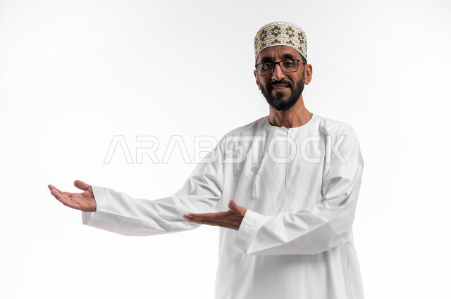 إشارات يد تدل على الترحيب، حسن الاستقبال والضيافة، بورتريه لرجل عماني شايب يرتدي الدشداشة والكمه تظهر عليه علامات الفرح والسرور، ابتسامة لطيفة تدل على المحبة، خلفية بيضاء
