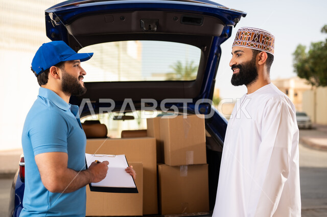 شحن الطلبات للزبائن، عملية التوصيل الآمنة والموثوقة ,مفهوم التسوق الالكتروني, شاب عربي خليجي عماني يرتدي الدشداشة و الكمة يقوم باستلام المشتريات، مندوب يحمل بيده أوراق و مستندات تأكيد تسليم الطرد للزبون
