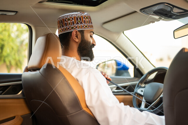 مفهوم القيادة الآمنة, خدمات توصيل و نقل الركاب, سائق عربي خليجي عماني يرتدي الدشداشة و الكمة يجلس في السيارة و يقوم بوضع حزام الأمان, مهن و وظائف عمانية