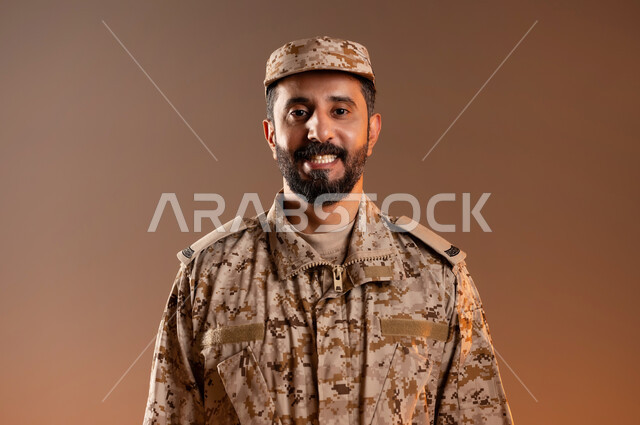 الدفاع عن الوطن، القوات المسلحة السعودية، الجيش العربي السعودي، بورتريه لرجل عربي سعودي خليجي يرتدي الزي العسكري يقف باستقامة وانضباط، ايماءات وجه مبتسمة، صورة الجسم بالطول الكامل، خلفية برتقاليه