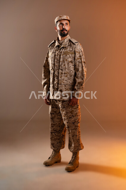 Rapid Intervention Forces, standing upright, prepared and disciplined, portrait of a Saudi Gulf Arab man wearing a military uniform standing in anticipation of a danger coming from afar (Falcon Eyes), maintaining security and safety, Saudi Armed Forces, orange background