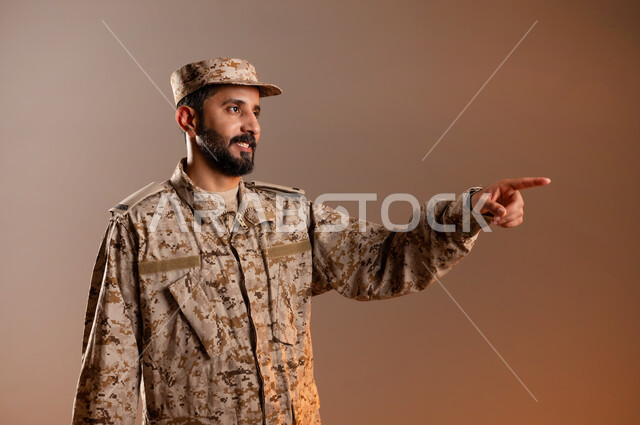 حركات تدل للذهاب الى مكان ما، التأمل وتحديد الاهداف بدقه، بورتريه لرجل عربي خليجي سعودي يرتدي الزي العسكري يشير بيده الى مكان معين، الوقوف والنظر الى موقع محدد والاشاره باصبع السبابه للوصول الى الهدف، القوات المسلحه السعوديه، خلفيه برتقاليه