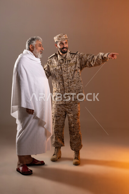 Helping pilgrims and Umrah pilgrims coming to Mecca to perform religious rituals, the gallantry of security personnel serving the guests of God, a portrait of a Saudi Gulf Arab man wearing a military uniform directing an elderly man wearing Ihram clothes to help him reach a place, orange background.