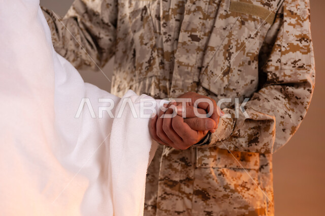 مساعده الحجاج والمعتمرين القادمين الى مكه المكرمه لاداء المشاعر الدينيه، شهامه رجال الامن في خدمه ضيوف الرحمن، بورتريه لرجل عربي خليجي سعودي يرتدي الزي العسكري يمسك بيد رجل كبير بالسن يرتدي ثياب الاحرام لمساعدته على الوقوف والمشي، خلفيه برتقاليه